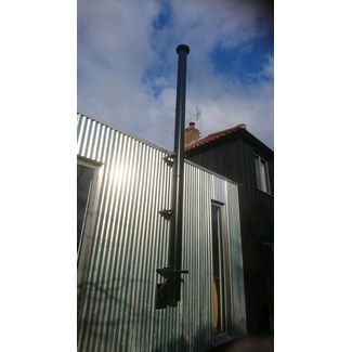 Black twin wall insulated chimney system through a corrugated metal sheet clad building