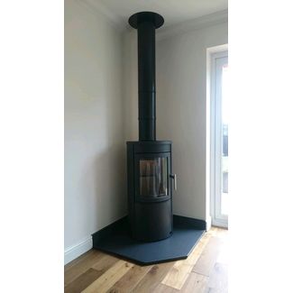 Tall contemporary round woodburner with a twin wall flue through the ceiling on a honed granite clipped corner hearth